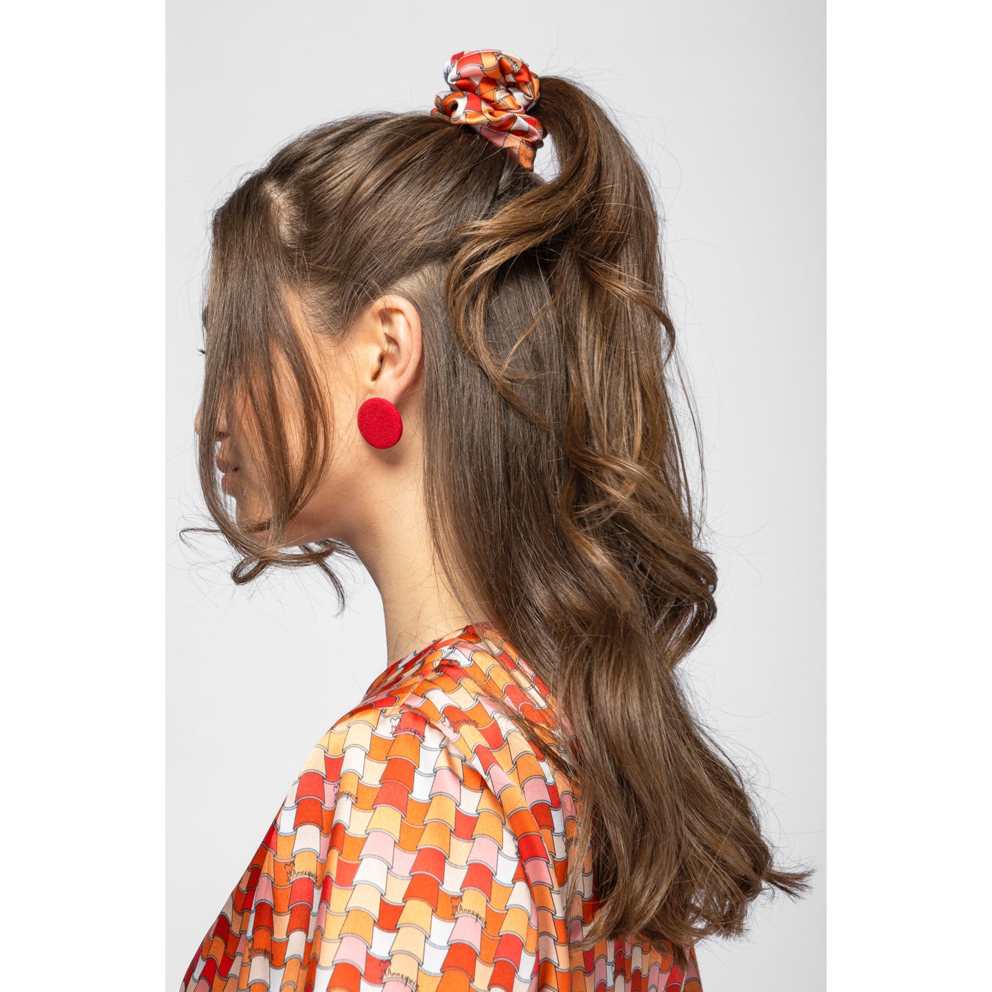 Woman with styled hair and colorful scrunchie on a white background